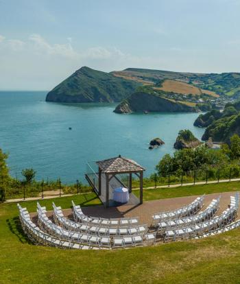 Outdoor wedding ceremony setup before guests arrive with arbour chairs and stunning panoramic sea views in the background