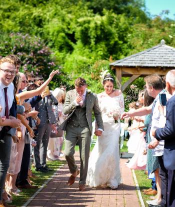 Bride and groom walking with confetti being thrown from their guests