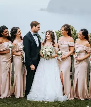A bride and groom standing outside The Venue at Sandy Cove Hotel with their bridesmaids