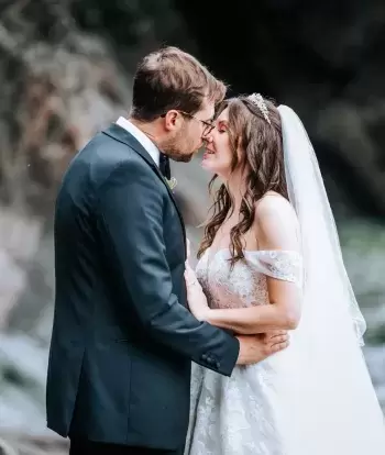 A bride and groom kissing on the beach by Sandy Cove Hotel on their wedding day