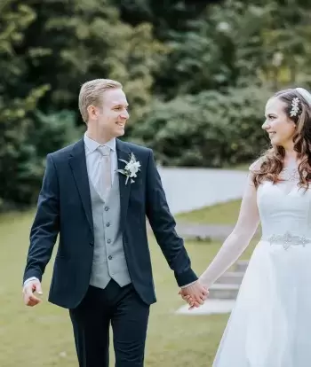 A bride and groom holding hands and walking outside The Venue at Sandy Cove Hotel