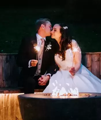 A bride and groom sharing a kiss by the firepit at Sandy Cove Hotel