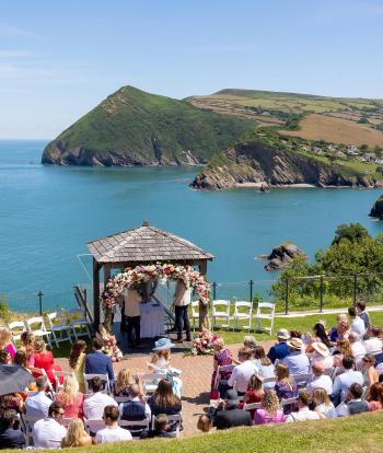 Wedding ceremony outside by the arbour with the view behind at the Sandy cove hotel