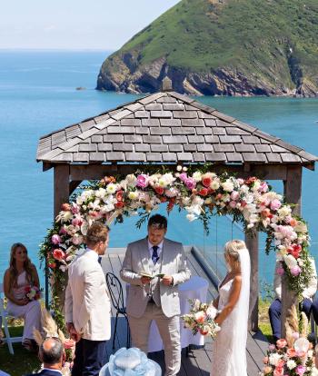 Wedding ceremony outside by the arbour with the view behind at the Sandy cove hotel