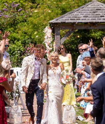 Bride and groom walking with confetti being thrown from their guests