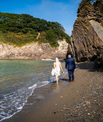 Bride and groom on the shore below Sandy Cove Hotel