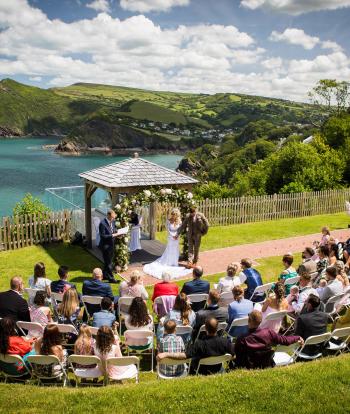 Wedding ceremony outside by the arbour with the view behind at the Sandy cove hotel