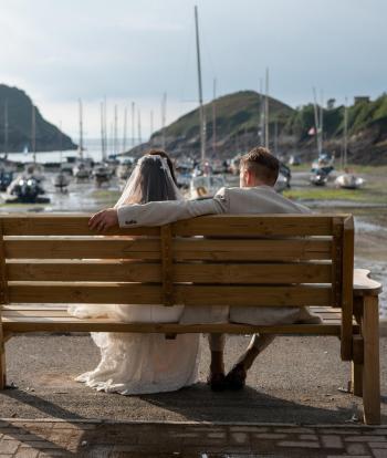 Bride and groom on the shore below Sandy Cove Hotel