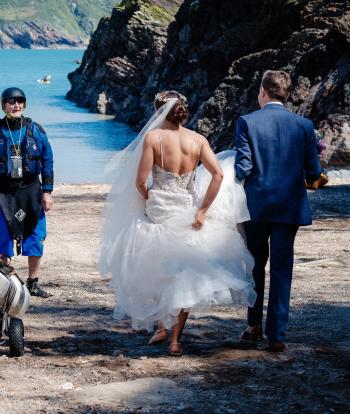 Newly wed couple walking toward beach in Combe Martin