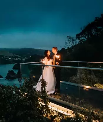 A bride and groom with sparklers on the platform outside The Venue, Sandy Cove Hotel