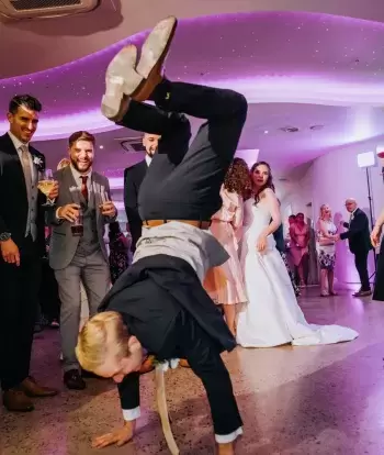 A groom showing off his dance moves to his bride and their wedding guests at The Venue, Sandy Cove Hotel