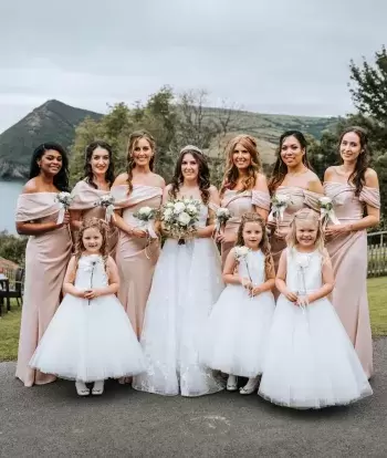 A bride standing with her bridal party in front of the view outside The Venue at Sandy Cove Hotel