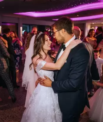 The bride and groom and entire wedding party dancing at the evening reception in The Venue at Sandy Cove Hotel