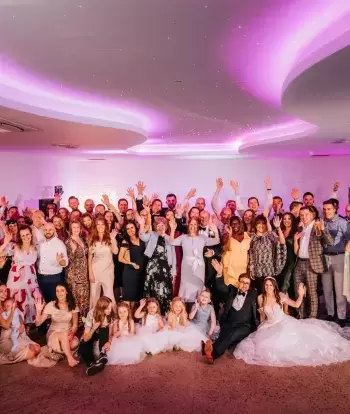 An entire wedding party posing for a photograph inside The Venue at Sandy Cove Hotel