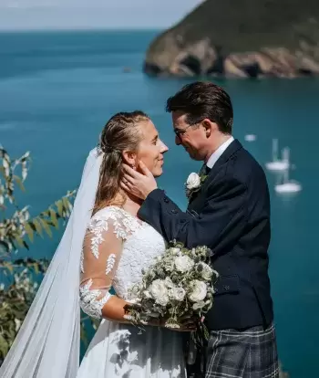 A newly married couple at The Venue, Sandy Cove Hotel, with a view over the bay behind them