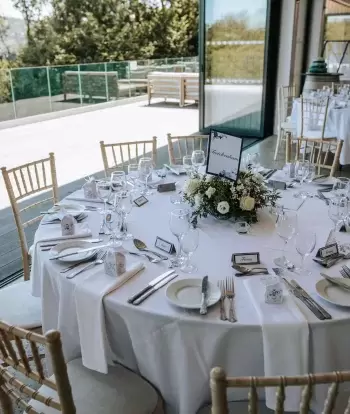 Tables by the bi-fold doors in The Venue at Sandy Cove Hotel dressed ready for a wedding reception