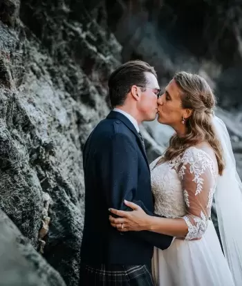 A newly married bride and groom kissing on the beach by Sandy Cove Hotel after their wedding ceremony