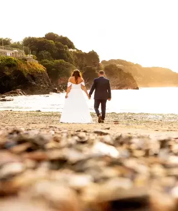 A newly-wed couple walking along the beach near Sandy Cove Hotel after their wedding