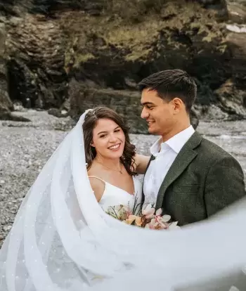 A happy newly-wed couple standing on the beach by Sandy Cove Hotel after their wedding ceremony