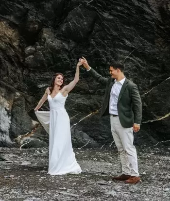 A bride and groom dancing on the beach by Sandy Cove Hotel after their wedding ceremony