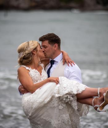 Bride and groom on the shore below Sandy Cove Hotel