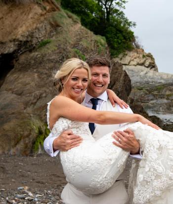 Bride and groom on the shore below Sandy Cove Hotel