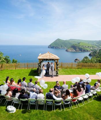 Wedding ceremony outside by the arbour with the view behind at the Sandy cove hotel