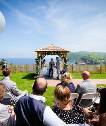 Wedding ceremony outside by the arbour with the view behind at the Sandy cove hotel