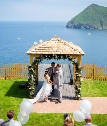 Wedding ceremony outside by the arbour with the view behind at the Sandy cove hotel