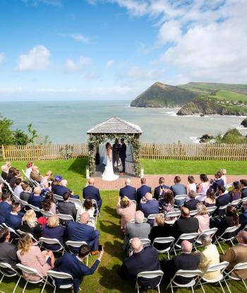 Wedding ceremony outside by the arbour with the view behind at the Sandy cove hotel