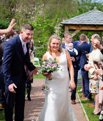 Bride and groom walking with confetti being thrown from their guests