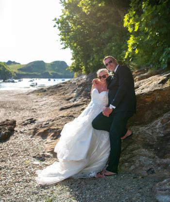 Bride and groom on the shore below Sandy Cove Hotel