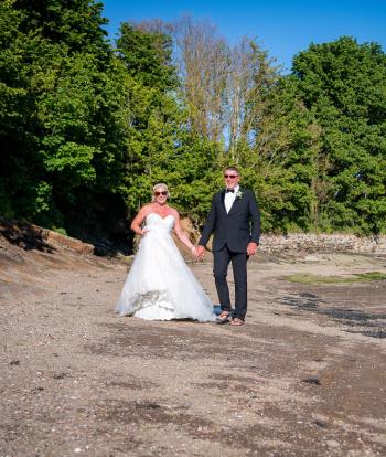 Bride and groom on the shore below Sandy Cove Hotel