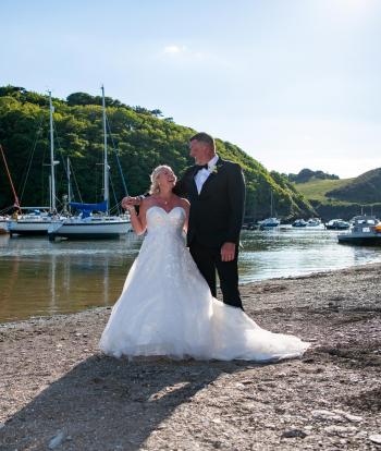 Bride and groom on the shore below Sandy Cove Hotel