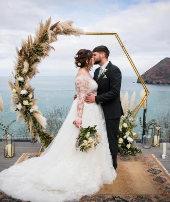 Bride and groom outside at the Sandy Cove Hotel, with the view behind them