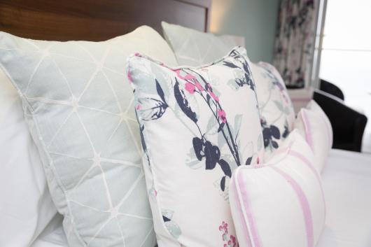 A close up of cushions and pillows on a bed in one of the rooms at Sandy Cove Hotel