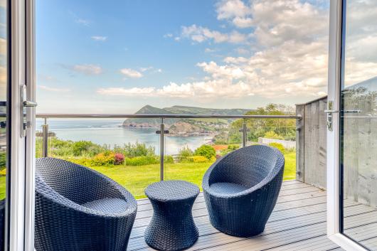 Two chairs and a table on the balcony overlooking the bay in Room 43 at Sandy Cove Hotel