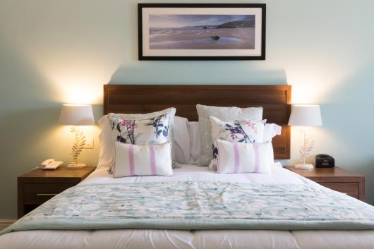 Cushions and pillows on a bed in one of Sandy Cove Hotel's bedrooms