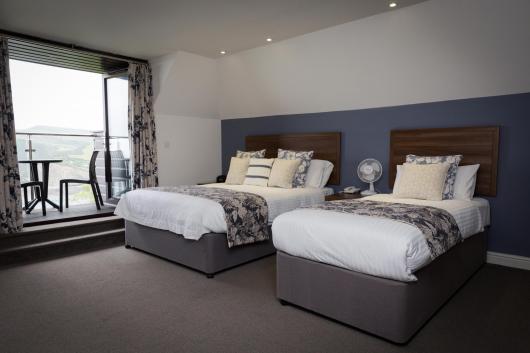Beds in a twin double room with a balcony at Sandy Cove Hotel