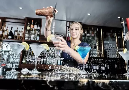 A bartender at Sandy Cove Hotel pouring a cocktail into a glass