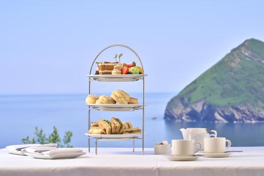 An afternoon tea with sandwiches, scones and cakes served with tea and coffee and with a view of the bay through the window