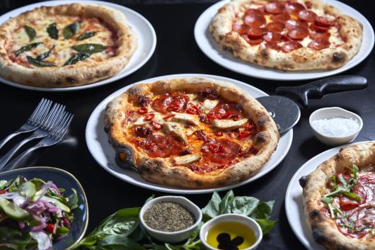 Various pizzas with cutlery on a table in one of Sandy Cove Hotel's restaurants