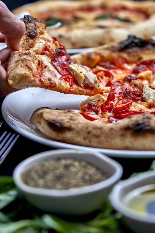 A close up view of a slice of pizza being lifted off a plate at Sandy Cove Hotel