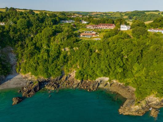 An aerial view showing Sandy Cove Hotel and The Venue with the sea in the foreground