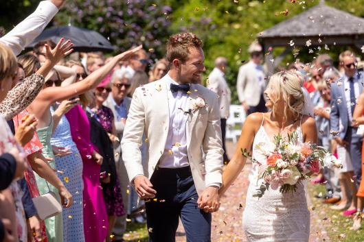 Guests throwing confetti over a bride and groom at Sandy Cove Hotel's the Venue