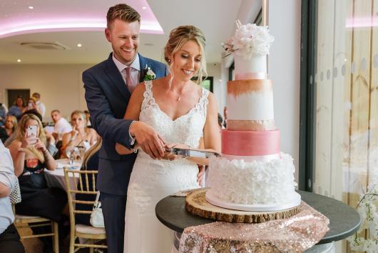 A bride and groom cutting the cake at their wedding at The Venue, Sandy Cove Hotel