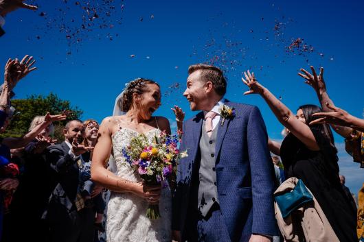 Guests throwing confetti over a bride and groom on their wedding day at Sandy Cove Hotel