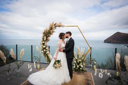 A bride and groom sharing a kiss on the deck of the Venue overlooking the bay