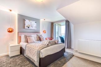 The bed and decor in a deluxe sea view bedroom with a balcony at Sandy Cove Hotel