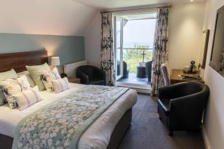 The bed and seating area inside a Superior Sea View with Balcony room at Sandy Cove Hotel